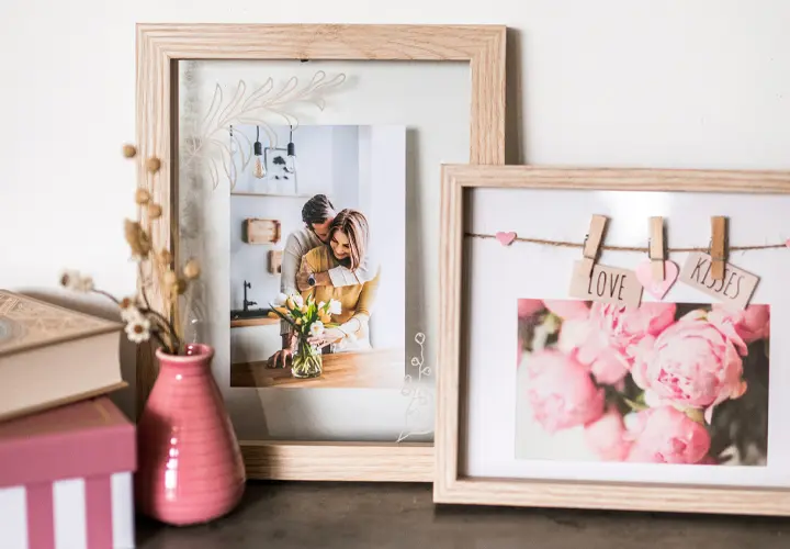 Eine gemütliche Auslage mit gerahmten Fotos und einer rosa Vase mit Blumen und dekorativen Schachteln