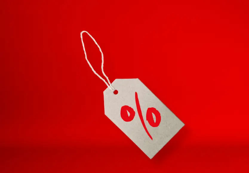 Ein graues Preisschild mit einem roten Prozentzeichen auf einem leuchtend roten Hintergrund, das Rabatte oder Sonderangebote symbolisiert. Ein graues Preisschild mit einem roten Prozentzeichen auf einem leuchtend roten Hintergrund, das Rabatte oder Sonderangebote symbolisiert.