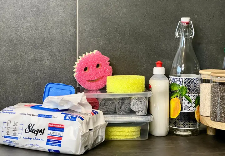 einigungszubehör in leuchtenden Farben auf dunkler Arbeitsfläche – mit einem fröhlich lächelnden Schwamm im Zentrum.