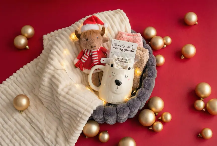 Eine gemütliche Feiertagsszene mit einem plüschigen Rentier, einer Bären-Tasse voller Kakao und Marshmallows, umgeben von goldenen Ornamenten.