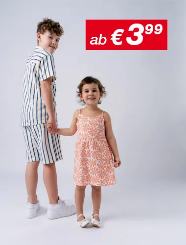 Ein Junge in einem gestreiften Outfit und ein Mädchen in einem geblümten Kleid halten sich lächelnd an den Händen, vor einem schlichten weißen Hintergrund.