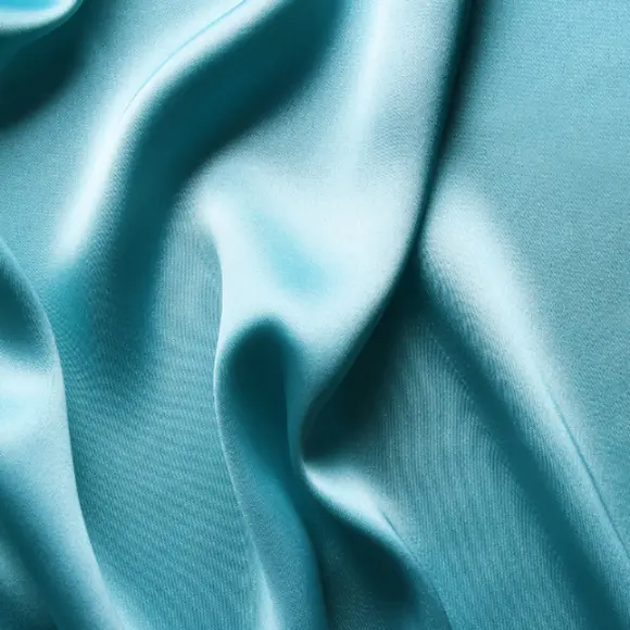 Nahaufnahme eines türkisen Satinstoffs, der im Licht schimmert.