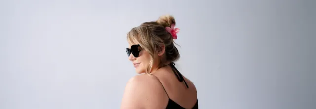 Zwei Frauen posieren selbstbewusst in Bikinis vor einem strahlend blauen Himmel und zelebrieren Körperbewusstsein und Sommerstimmung.