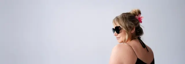 Zwei Frauen posieren selbstbewusst in Bikinis vor einem strahlend blauen Himmel und zelebrieren Körperbewusstsein und Sommerstimmung.