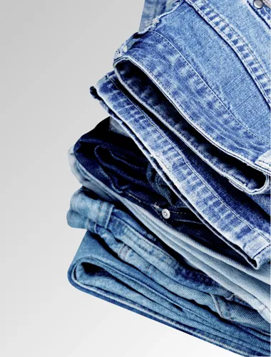 verschiedene Jeans, die zusammengefaltet und gestapelt übereinander liegen auf einem weißen Hintergrund.