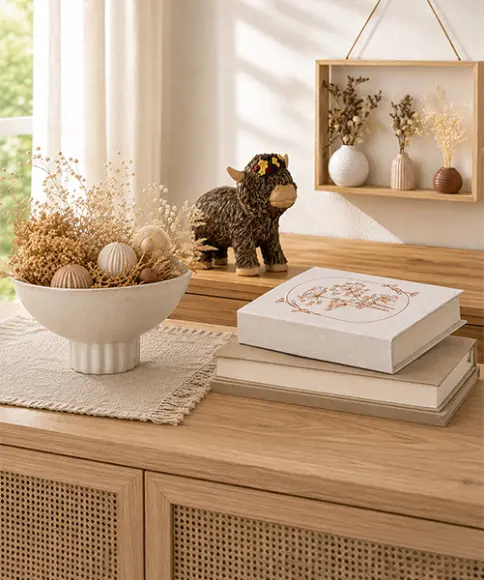 Dekorative Wohnaccessoires aus Naturmaterialien auf einer Holzkommode – Trockenblumen, Schale und Tierfigur im natürlichen Wohnstil