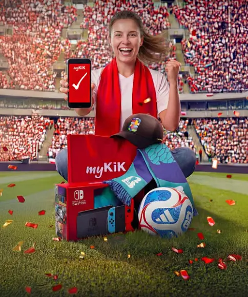 Eine Person in einem Stadion hält ein Smartphone mit der myKiK‑App, umgeben von einer Nintendo Switch, einem Fußball, einer Kappe, einem Schal und einem myKiK‑Paket.