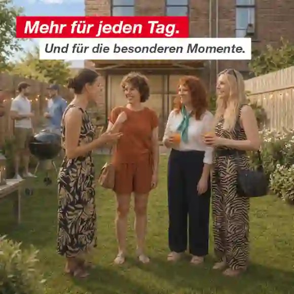 Gruppe von Menschen unterhält sich und genießt Getränke in einem Hinterhofgarten mit Holzzaun und Lichterketten.