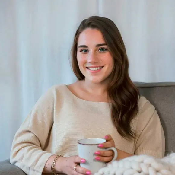 Eine Frau sitzt auf einem Sofa und hält eine Tasse Kaffee in der Hand.