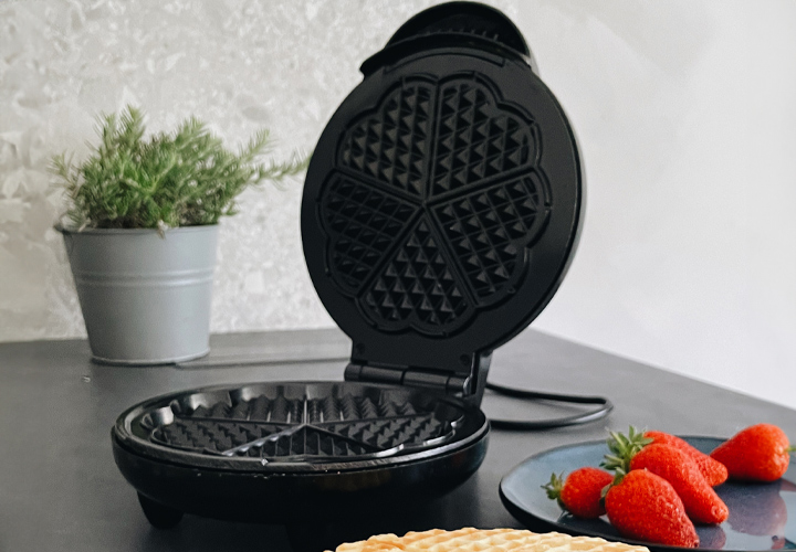 Ein Waffeleisen mit leckeren Waffeln und Erdbeeren.