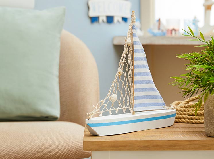 Ein dekoratives Modellsegelboot mit gestreiftem Segel steht auf einem Holztisch